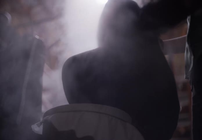 Hands of a person preparing tea under smoke in an indoor space