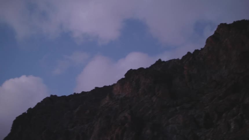 A large rocky mountain rises majestically against a cloudy sky