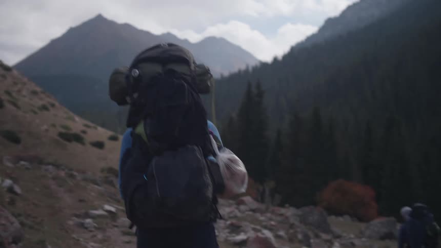 Person with big backpacks walking on mountain path during the day