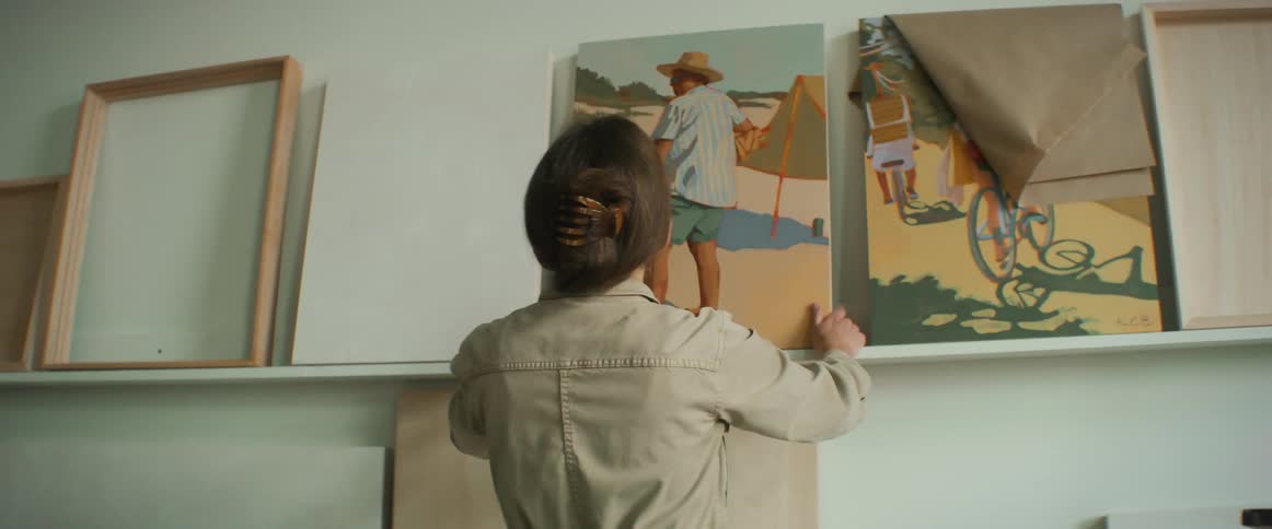 A woman is placing a painting on a wall