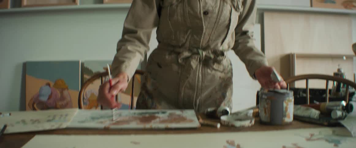 Painter putting paint and painting with a brush on a canvas on the table