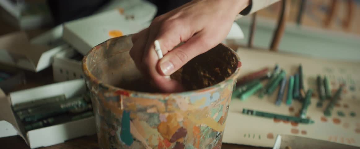 A person holding a brush in a pot of paint