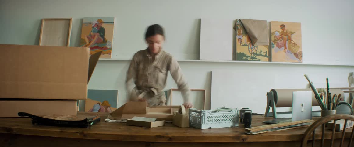 A woman is packing paintings into boxes
