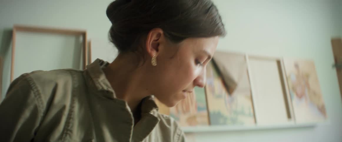 Woman holds paintbrush and looks for something to her left