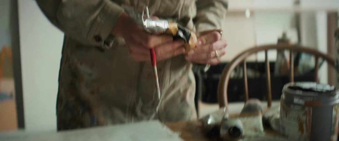 Closeup of a womans hands applying paint on a painting canvas and using a brush