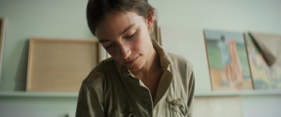 A concentrated woman with a room with paintings on the wall
