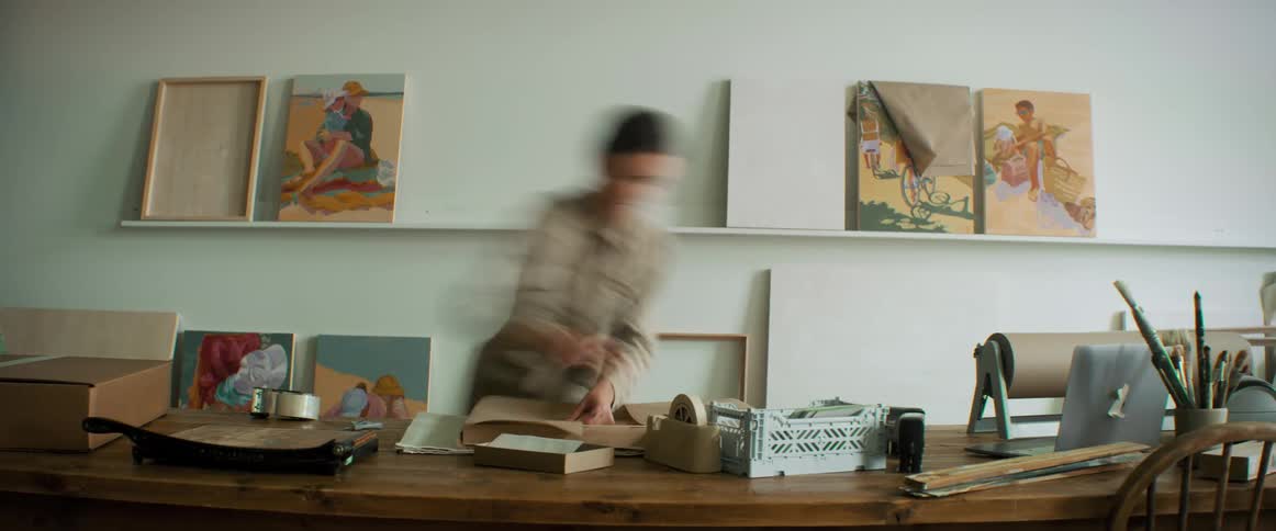 A woman packing paintings into cardboard houses in an office