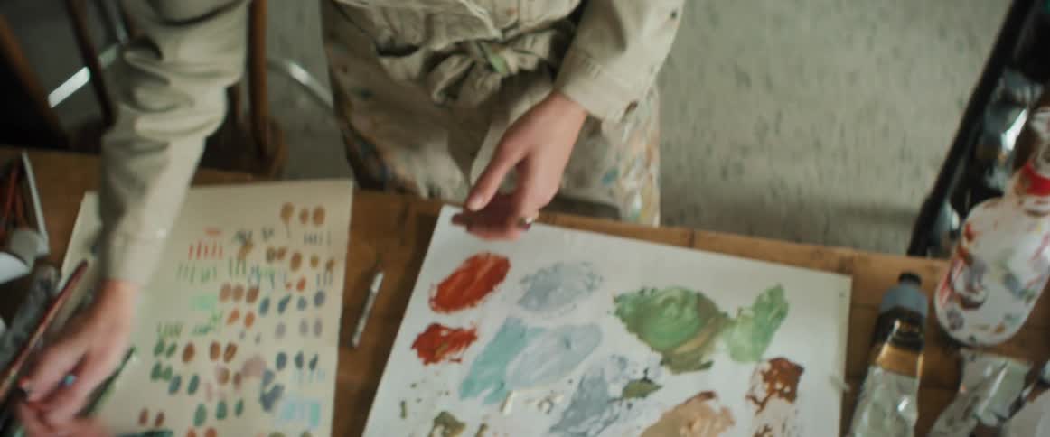 Closeup of a painters hands holding a chalk and testing it on paper