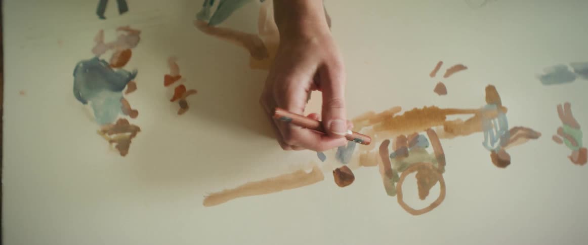 A persons hand with a chalk is painting a drawing on a board
