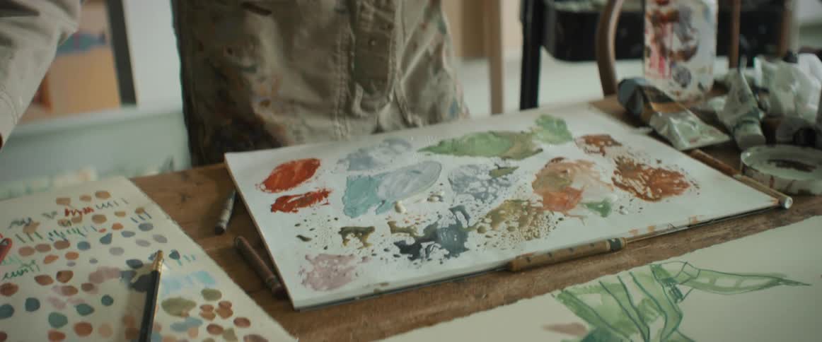 Closeup of a painters hands splashing water onto a brush and canvas with paint