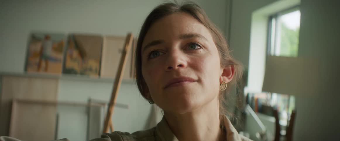 A woman is smiling as she paints