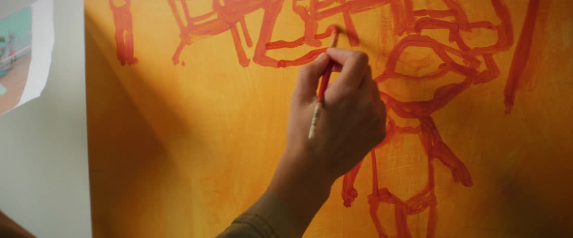 Painter painting a canvas while holding an image with the other hand
