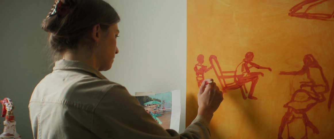 Woman painting on a canvas with a printed photo beside her