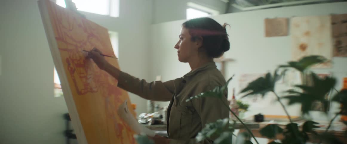 Woman painting a picture while looking at an image