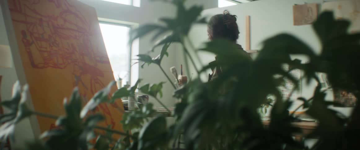 Painter picking up paint next to a canvas in an indoor room