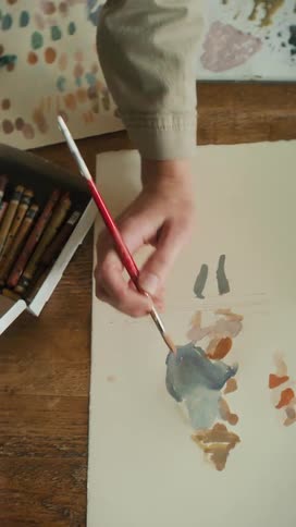 A person dipping a brush into a pan of water