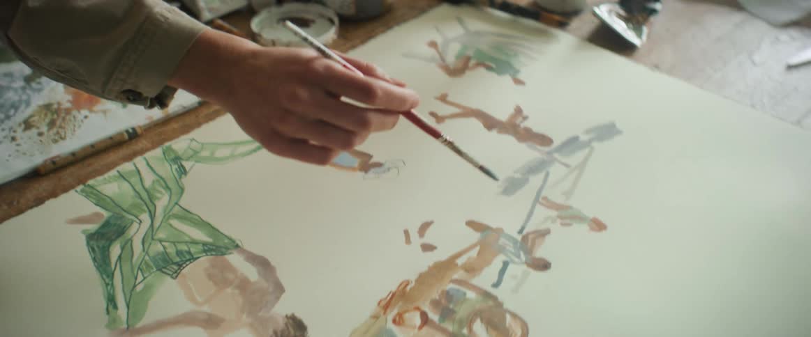 A woman painting a picture at her work table