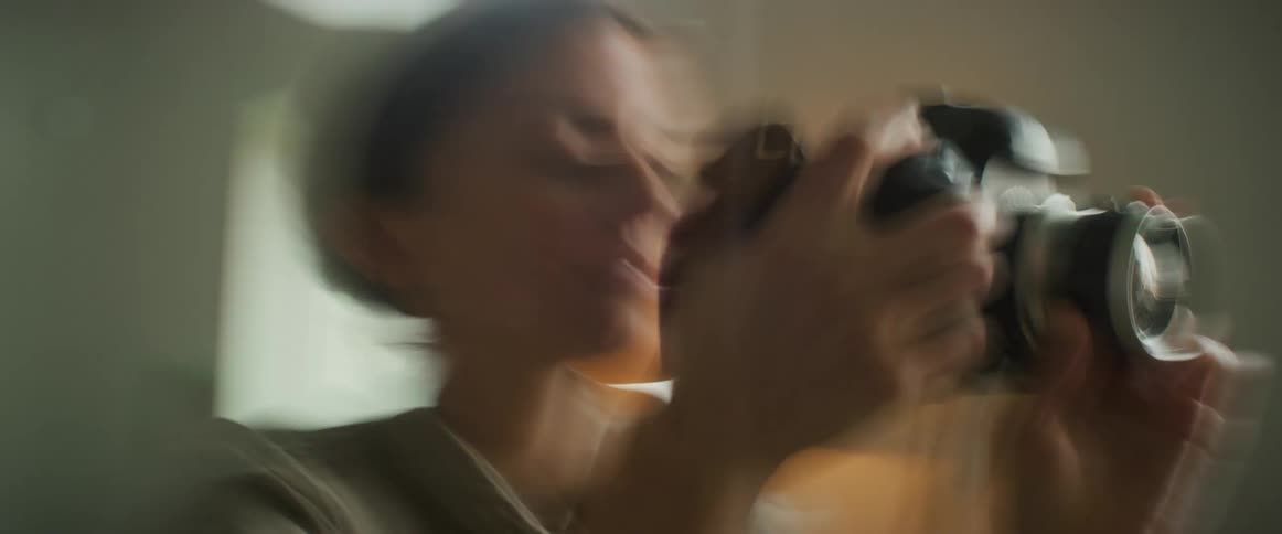 Portrait of a woman taking a photo with a professional camera in an indoor setting