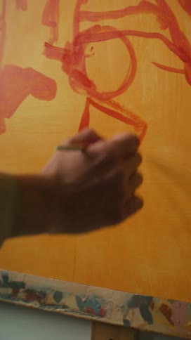 Hand with paintbrush painting on a canvas