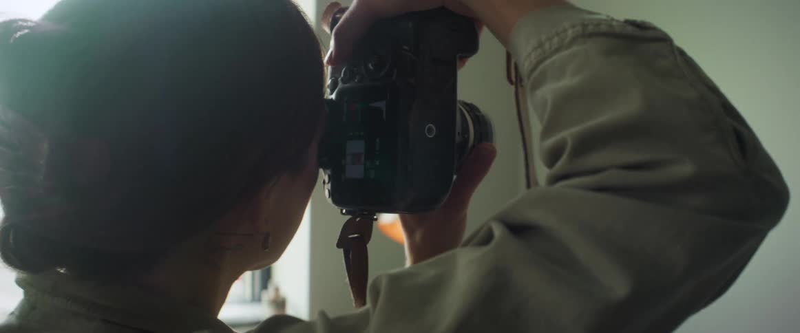 A woman photographing a painting on the wall