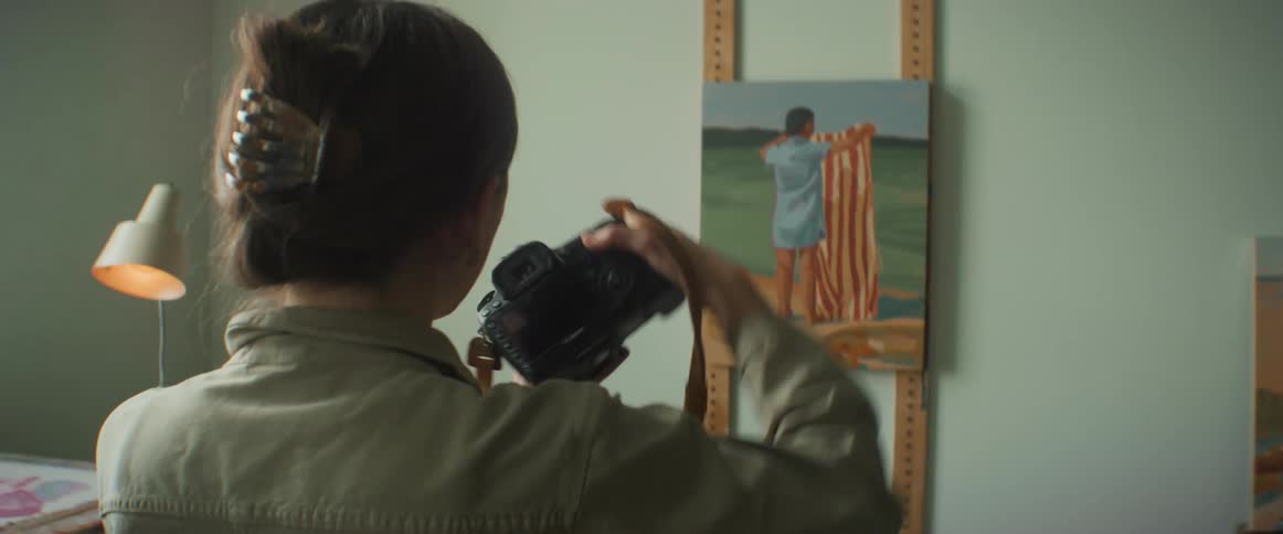 Woman uses a camera to take pictures of a painting