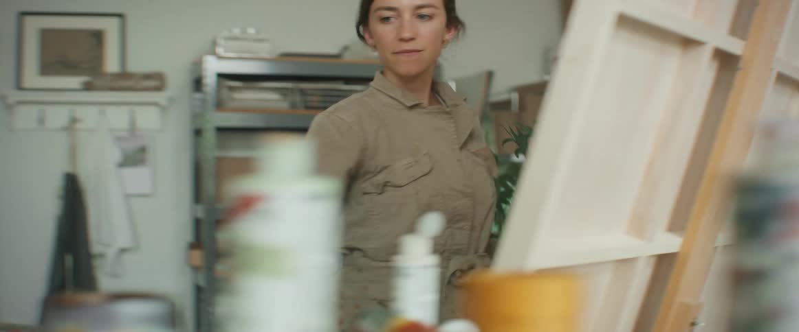 Lady painting on a canvass at midday in an art work studio