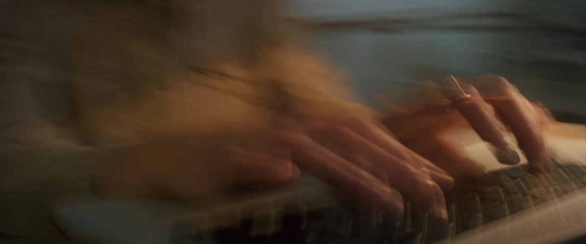 A man typing on a laptop while seated indoor