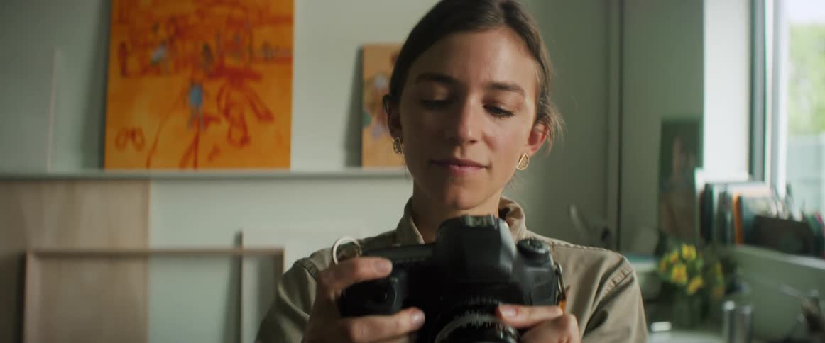 Portrait of a woman taking a photo with a professional camera in an indoor setting