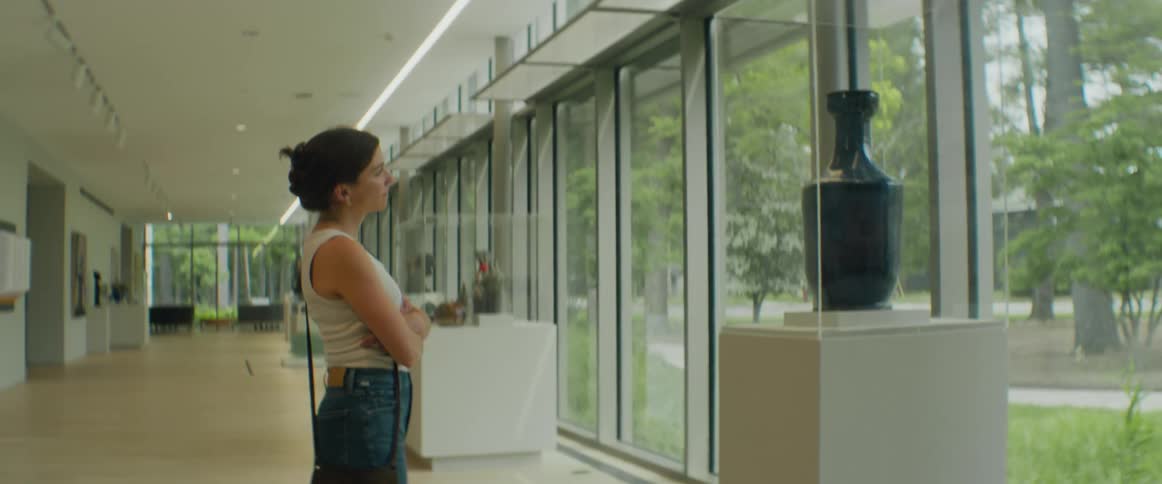 A young woman looks upon a vase on display in a museum