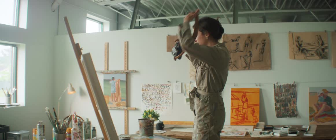 Woman grabbing a chair climbing on it and taking a photo of artwork
