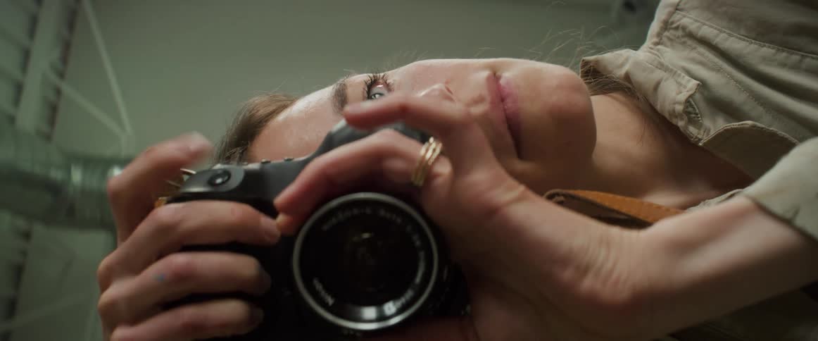Woman picking up a professional camera and adjusting it