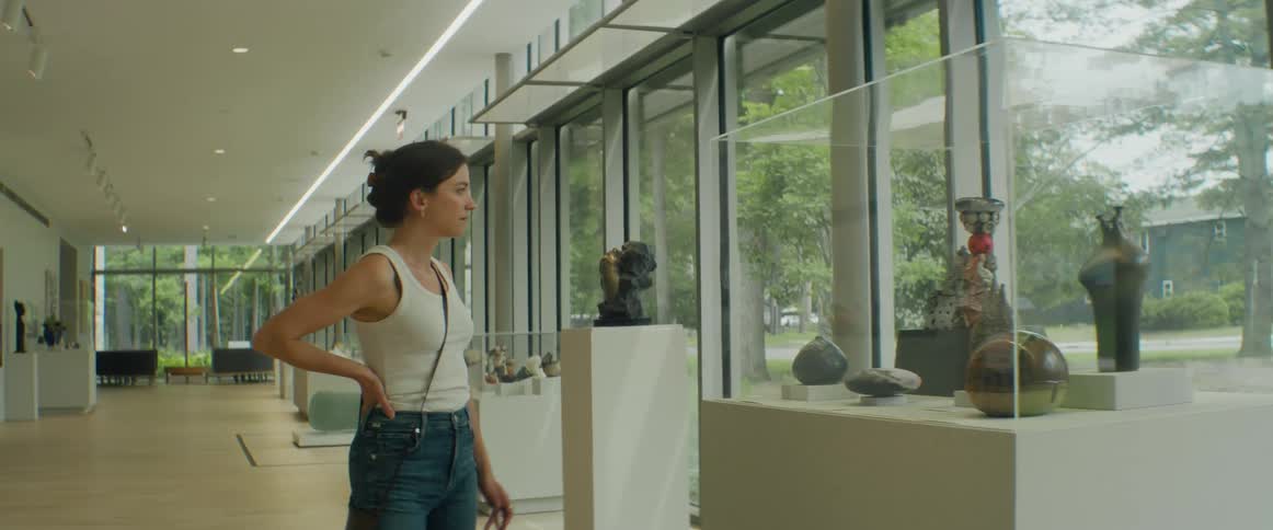A woman walks through an art museum while browsing art displays