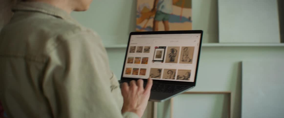 Woman standing looking at artworks on her laptop