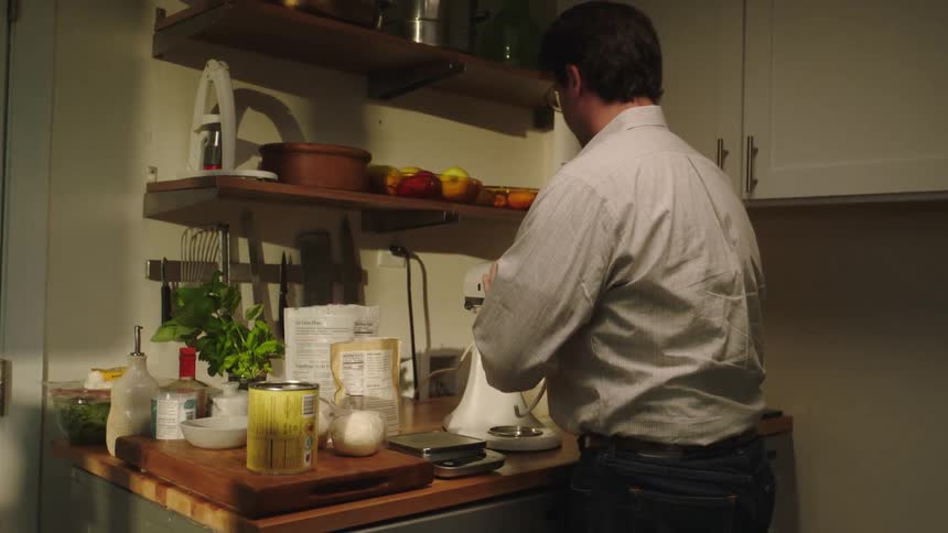 A man in the kitchen separates ingredients to prepare a meal