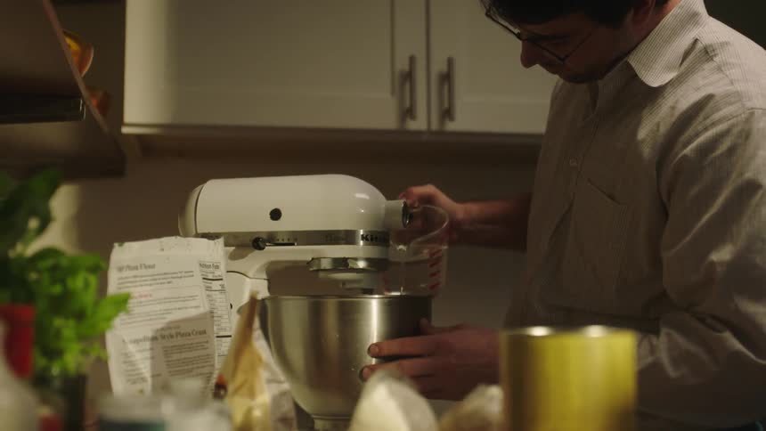 Man pour water inside a working mixer in the kitchen