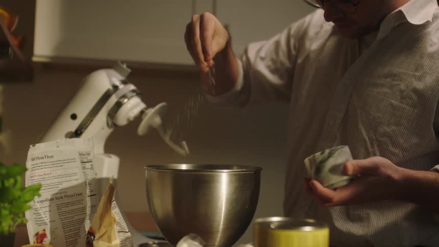 Man cooking adding a powder into a bowl in the mixer