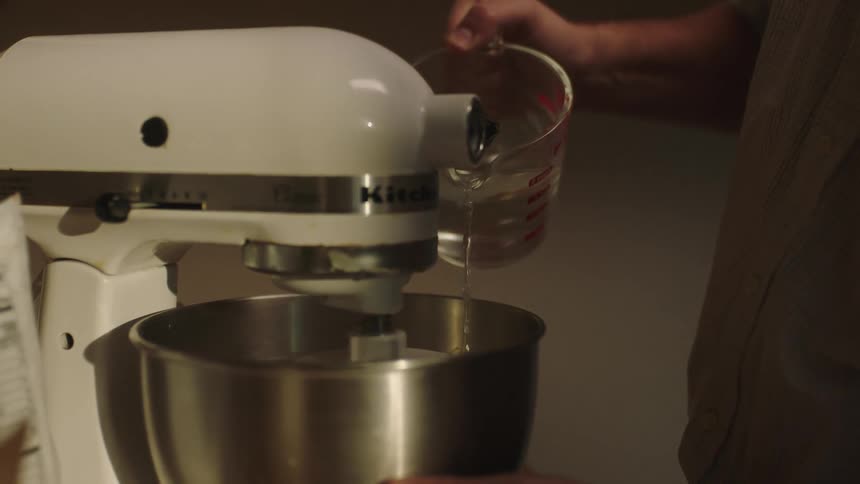 Man pours liquid inside a mixer in the kitchen
