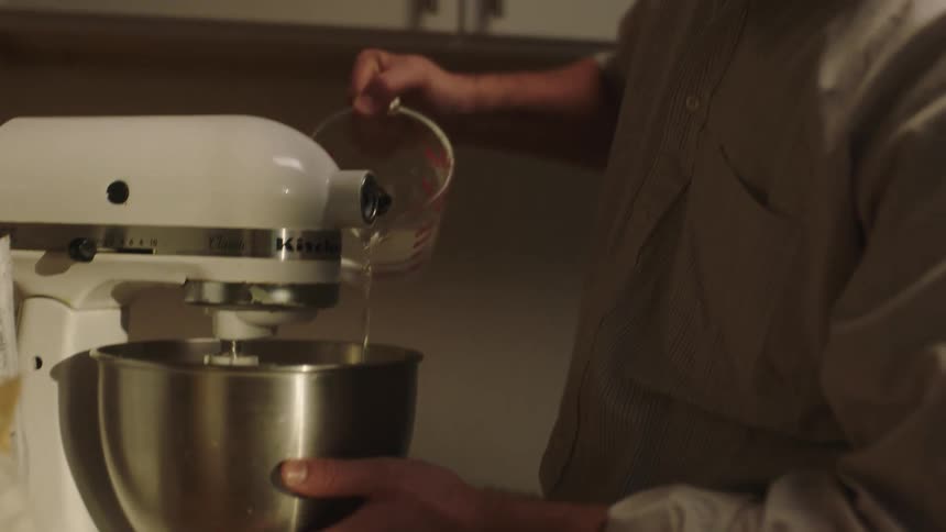 Hands of a man pouring water into a mixer