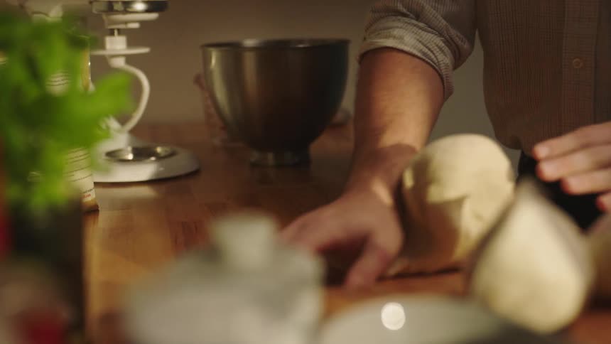 A man kneads bread dough on a kitchen countertop