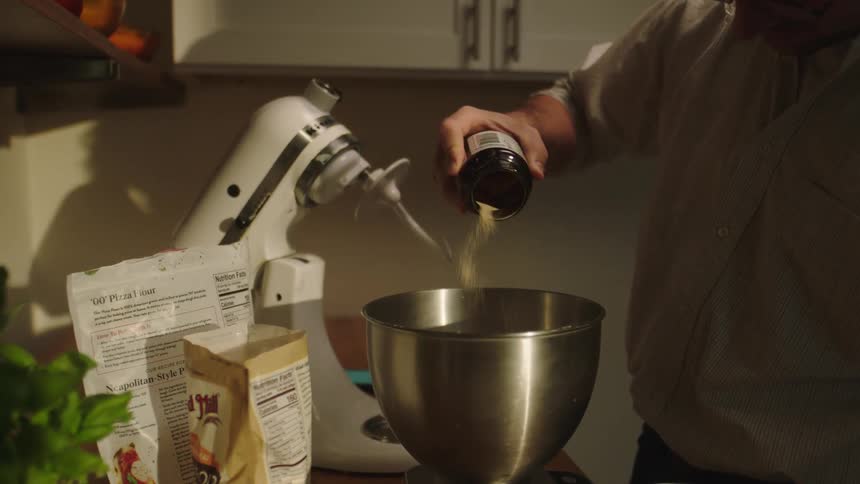 Man pour food ingredient inside a stainless bowl while standing in the kitchen