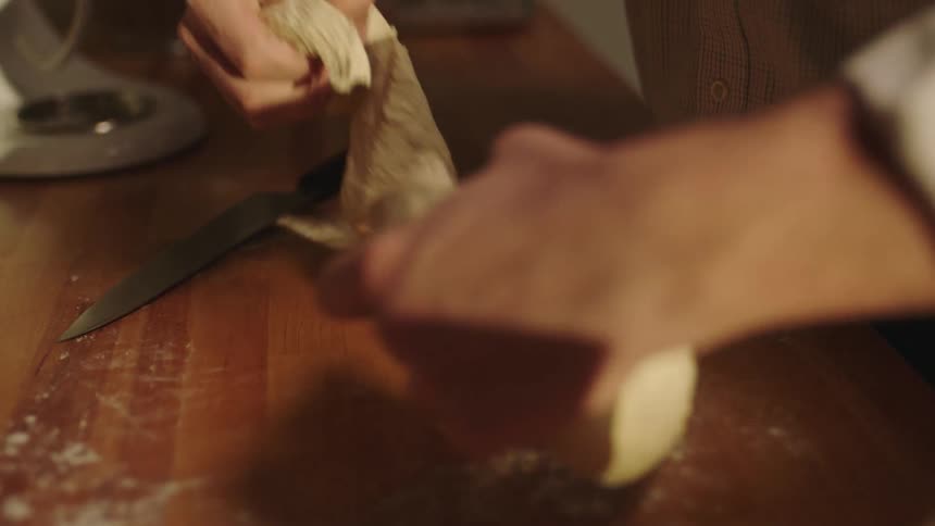 Man uses a sharp kitchen knife to cut dough