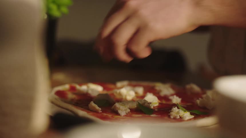 A persons hand preparing pizza