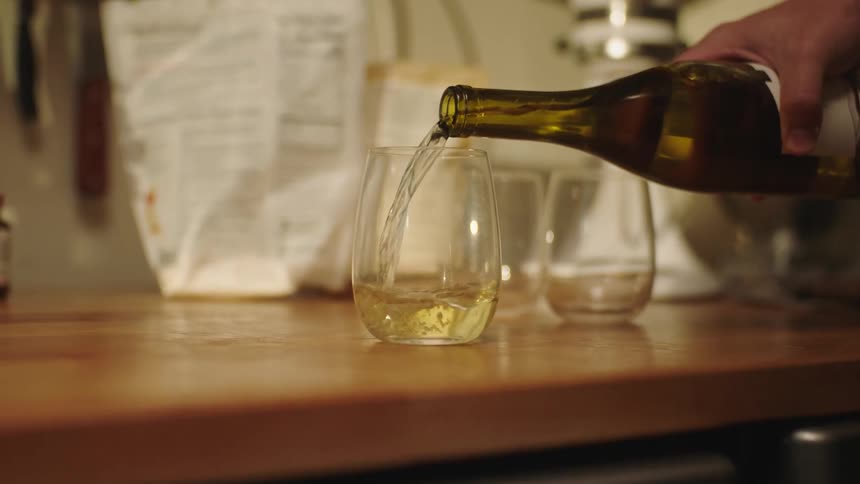 A person turning wine into a glass