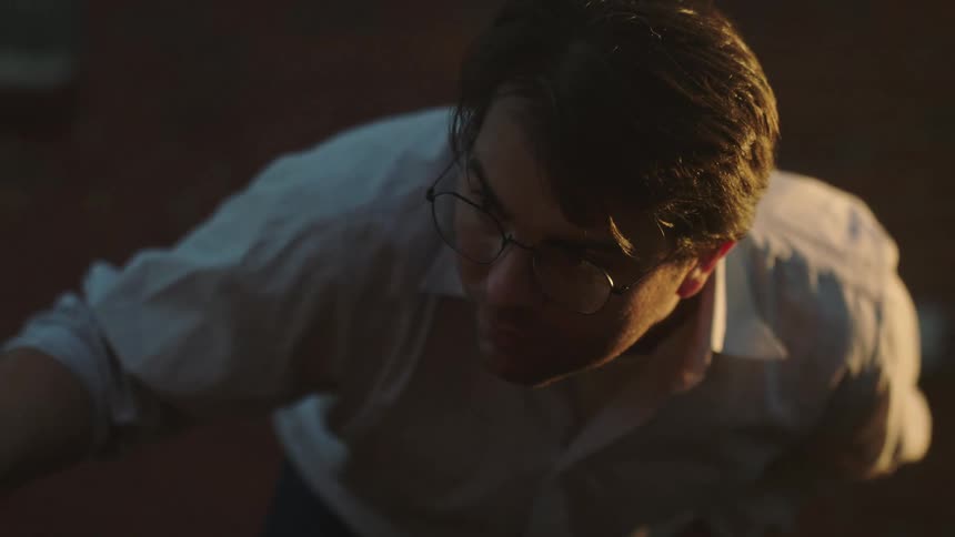 Portrait of a man with glasses manipulating an object with one hand