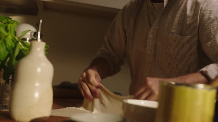 Closeup of a mans hands preparing dough on a countertop