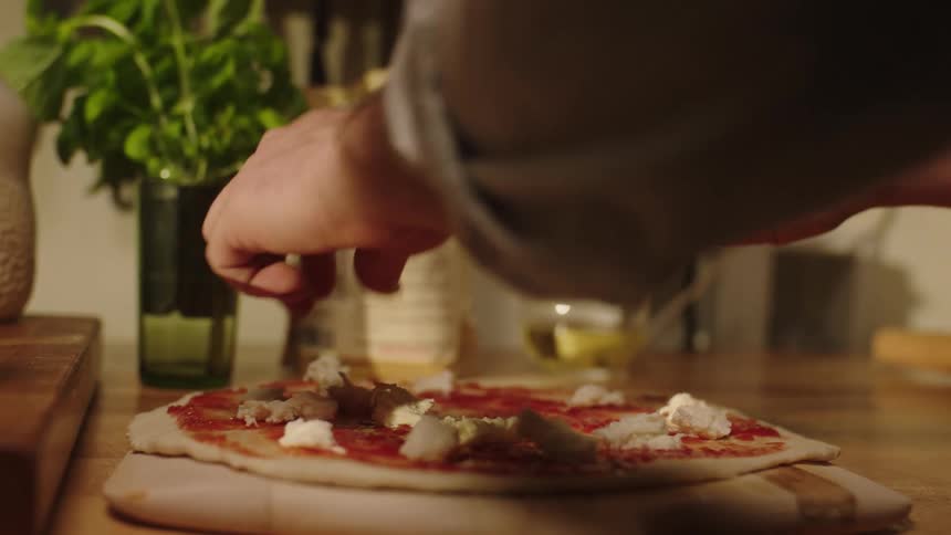 A person making mozzarella pizza at home
