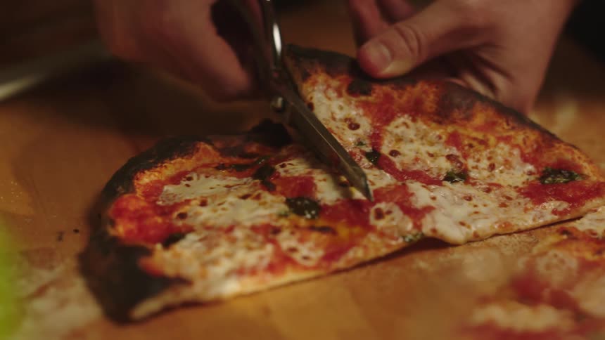 A person cutting pizza dough with scissors