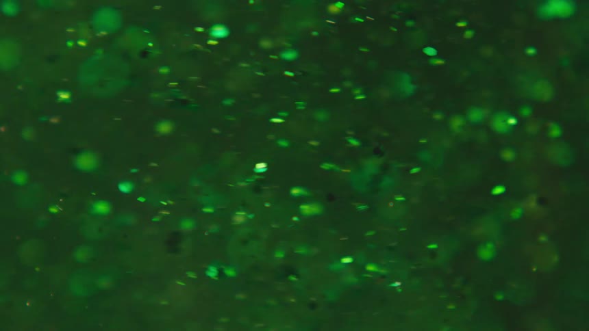 Several green particles with reflections moving to the left