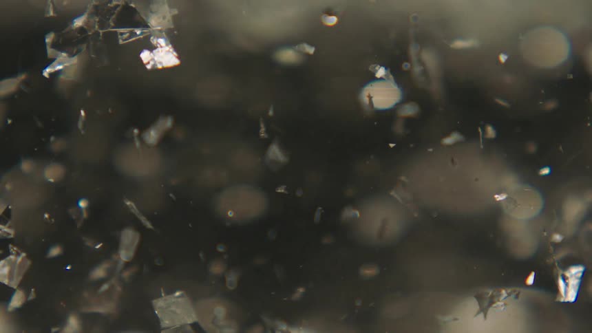 Extreme closeup of sparkling glitter in water in slow motion