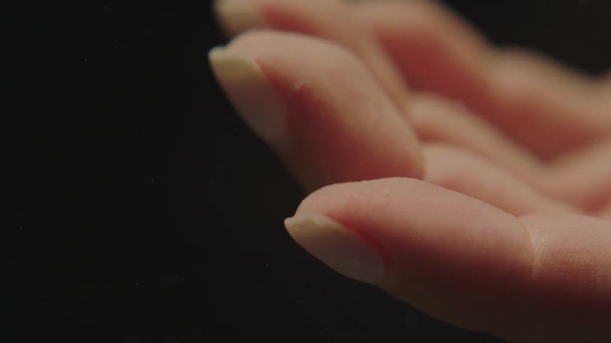 Close up of the hand of a woman against a black background